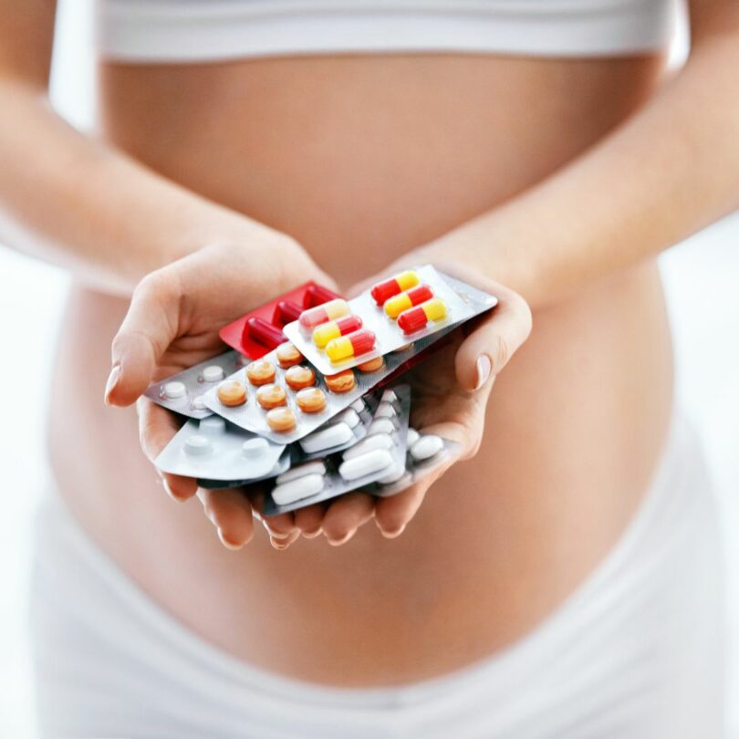 pregnant woman holds different drugs and medicines in her hand